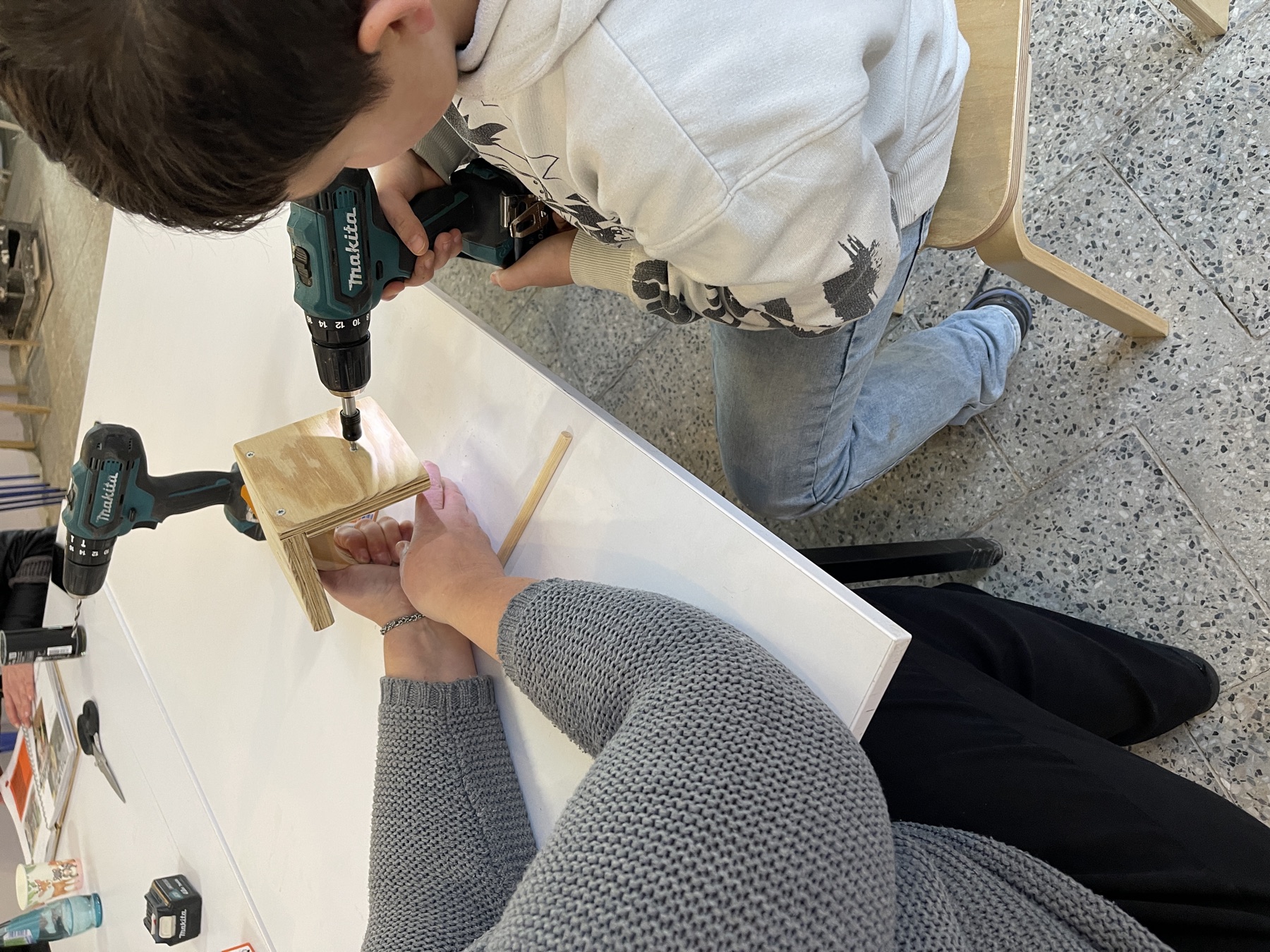 Kind arbeitet mit einem Akkuschrauber an einem Holzstück